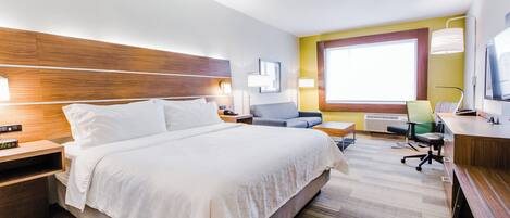 Ein Hotelzimmer mit einem großen Bett, einem Schreibtisch, einem Sessel und einem Fernseher.
