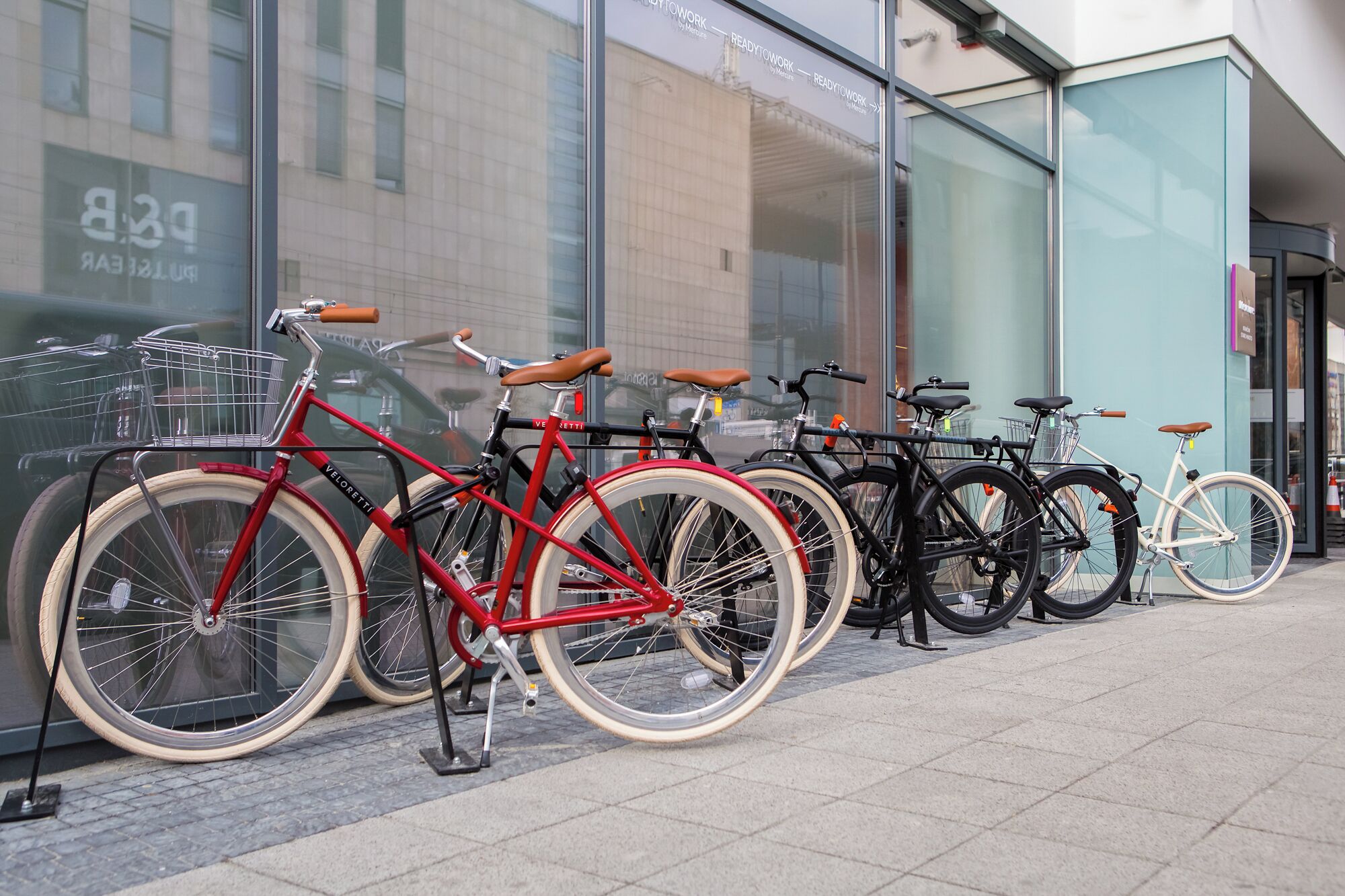 A row of bicycles parked outside a building with large windows.