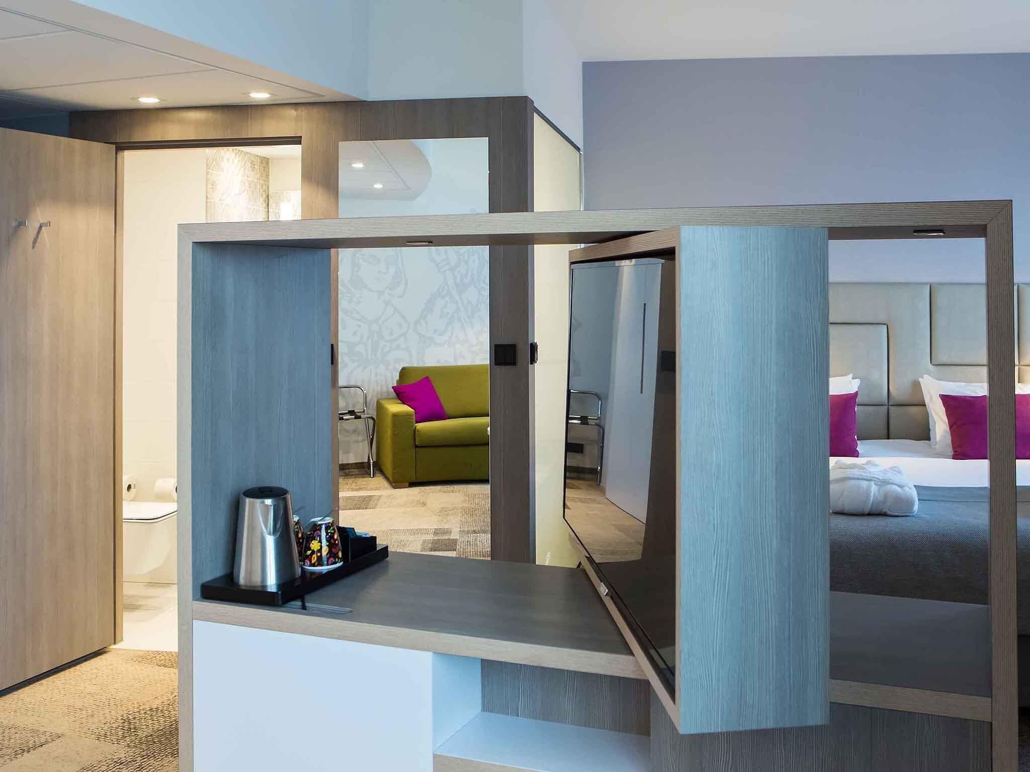 Una habitación de hotel moderna con cama, sofá y una mesa de centro.
