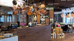 A modern bar area with a wooden counter, hanging copper pots, and a menu board. - Mercure Krakow Stare Miasto (Old Town) (Kraków)