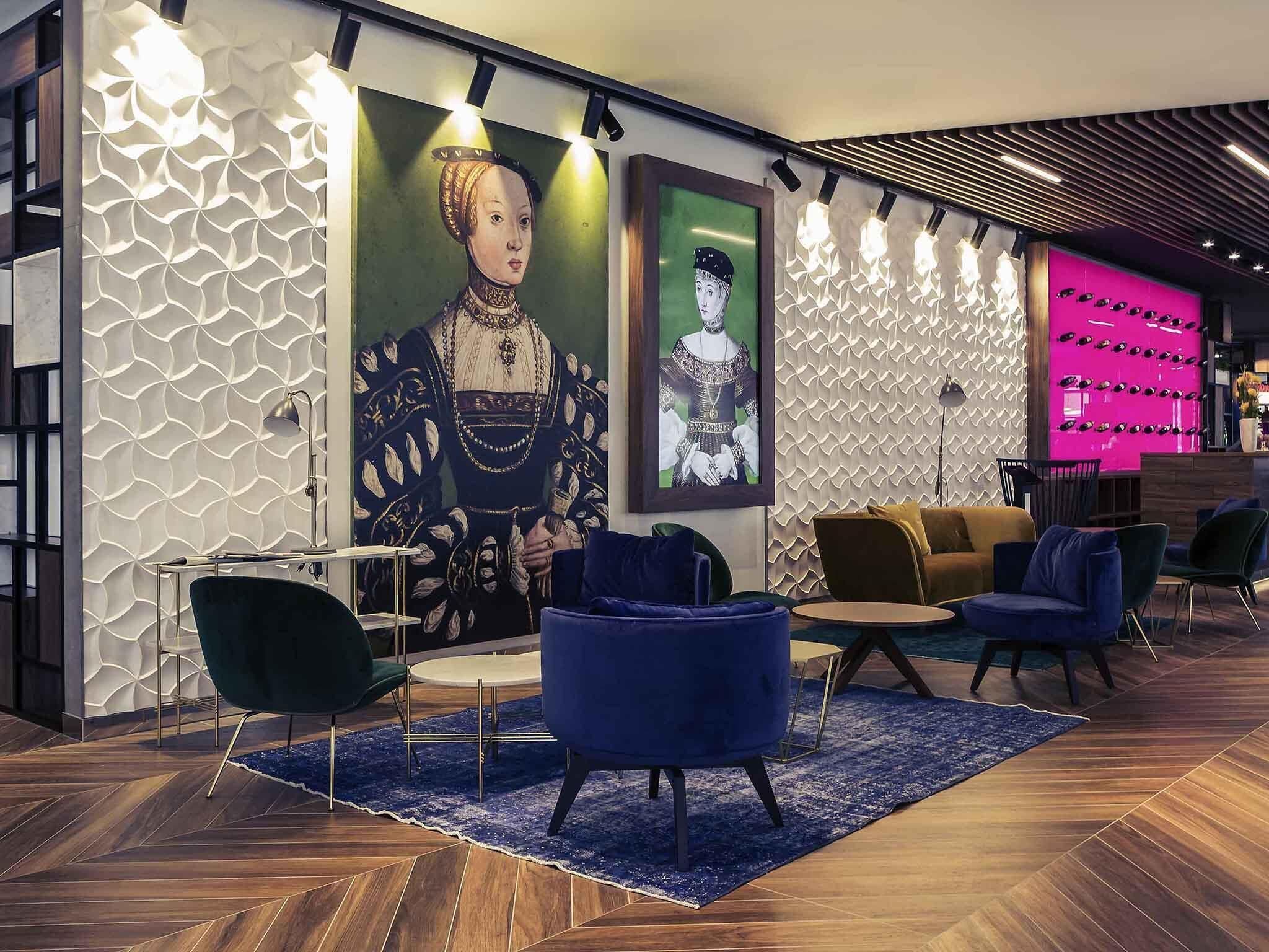 A modern lobby with a large mural, seating area, and a bar.