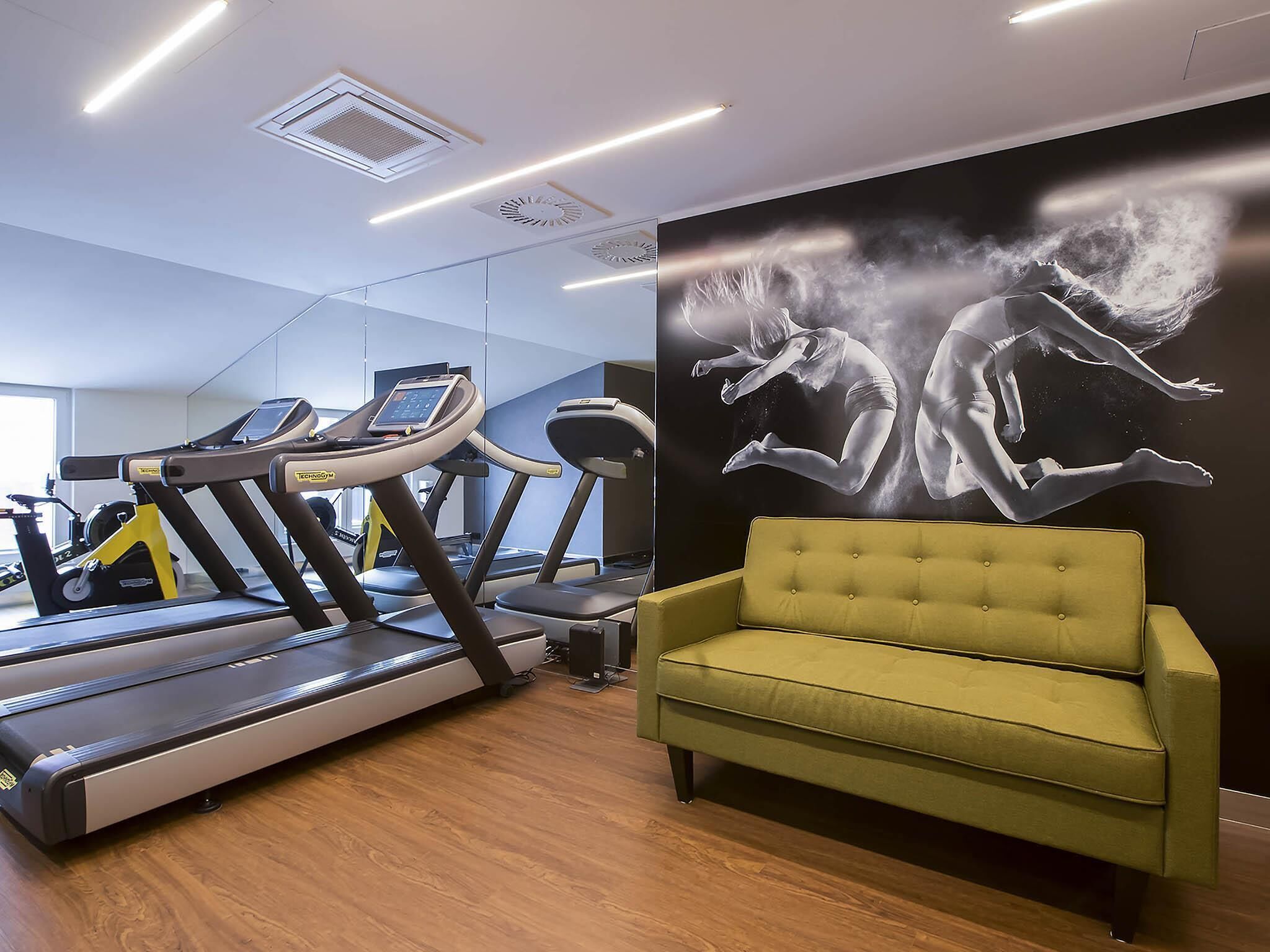 A gym with treadmills and a large wall mural.