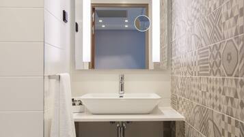 A bathroom with a white sink, a mirror, and patterned tiles.