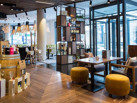 Un interno moderno con parquet, un angolo bar con bottiglie di vino e una zona salotto con pouf gialli.. Mercure Krakow Stare Miasto (Old Town)