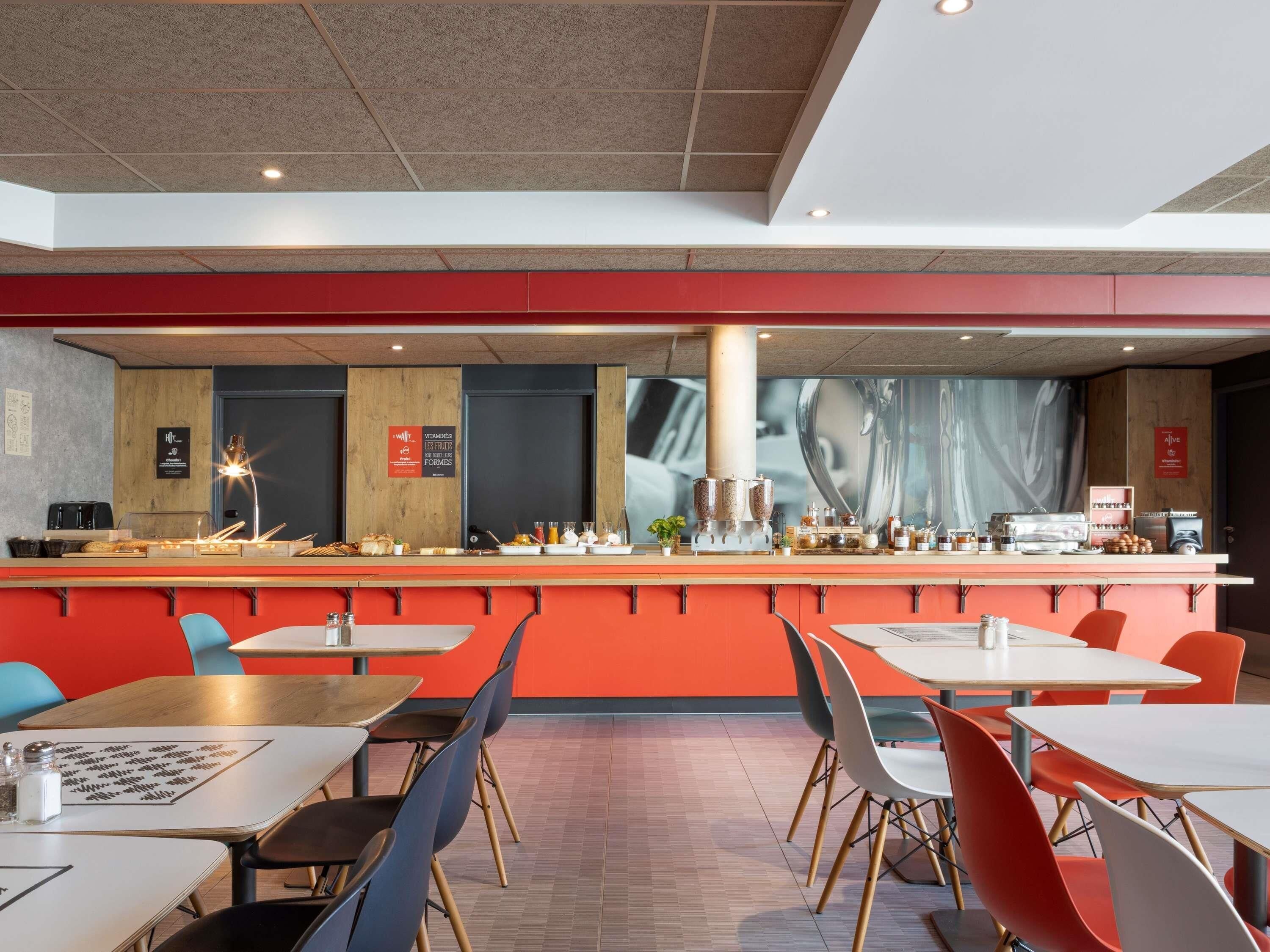 A modern cafe with a long counter, seating area, and a large window.