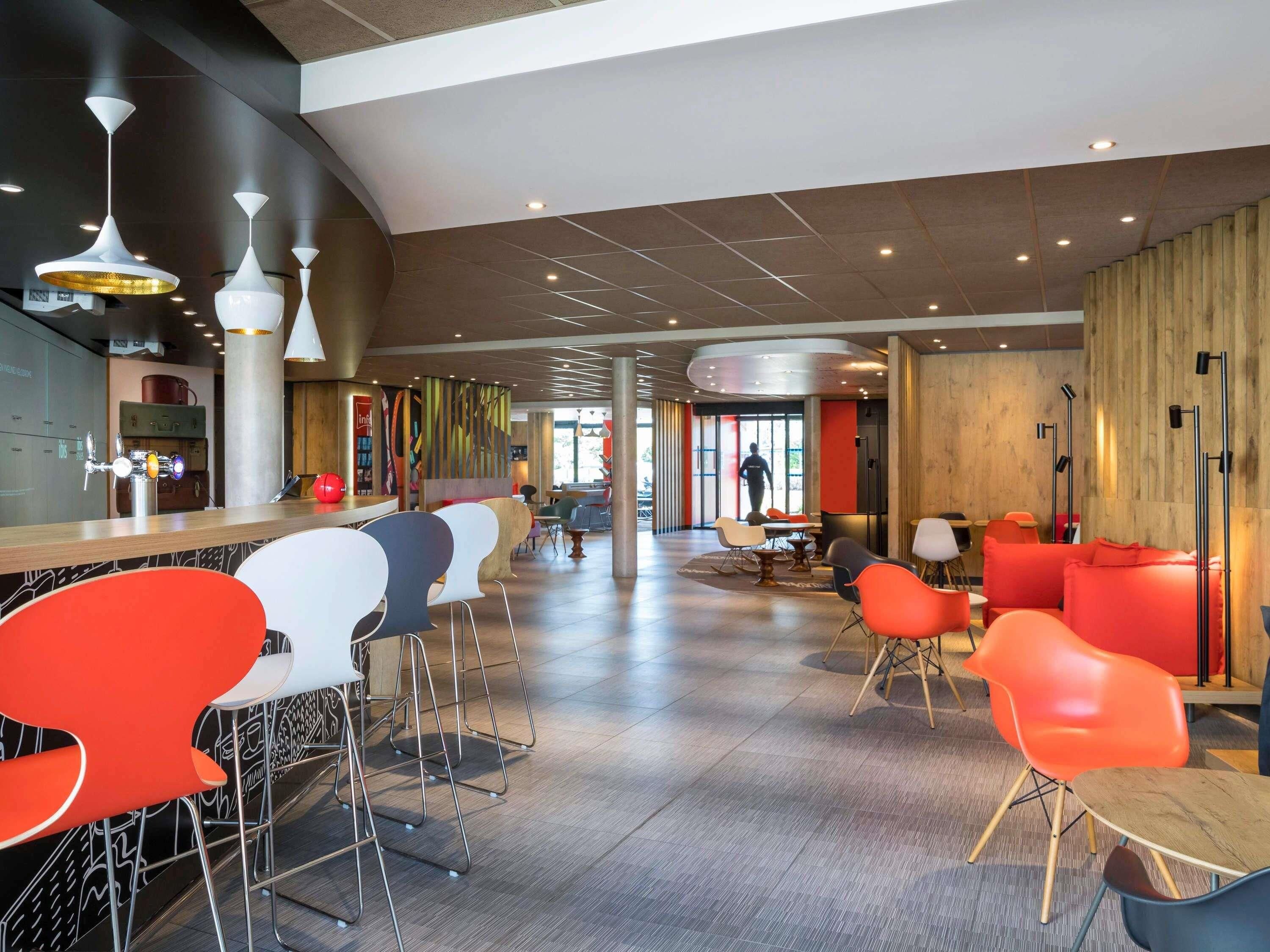 A modern interior with a bar area, seating with colorful chairs, and a spacious layout.