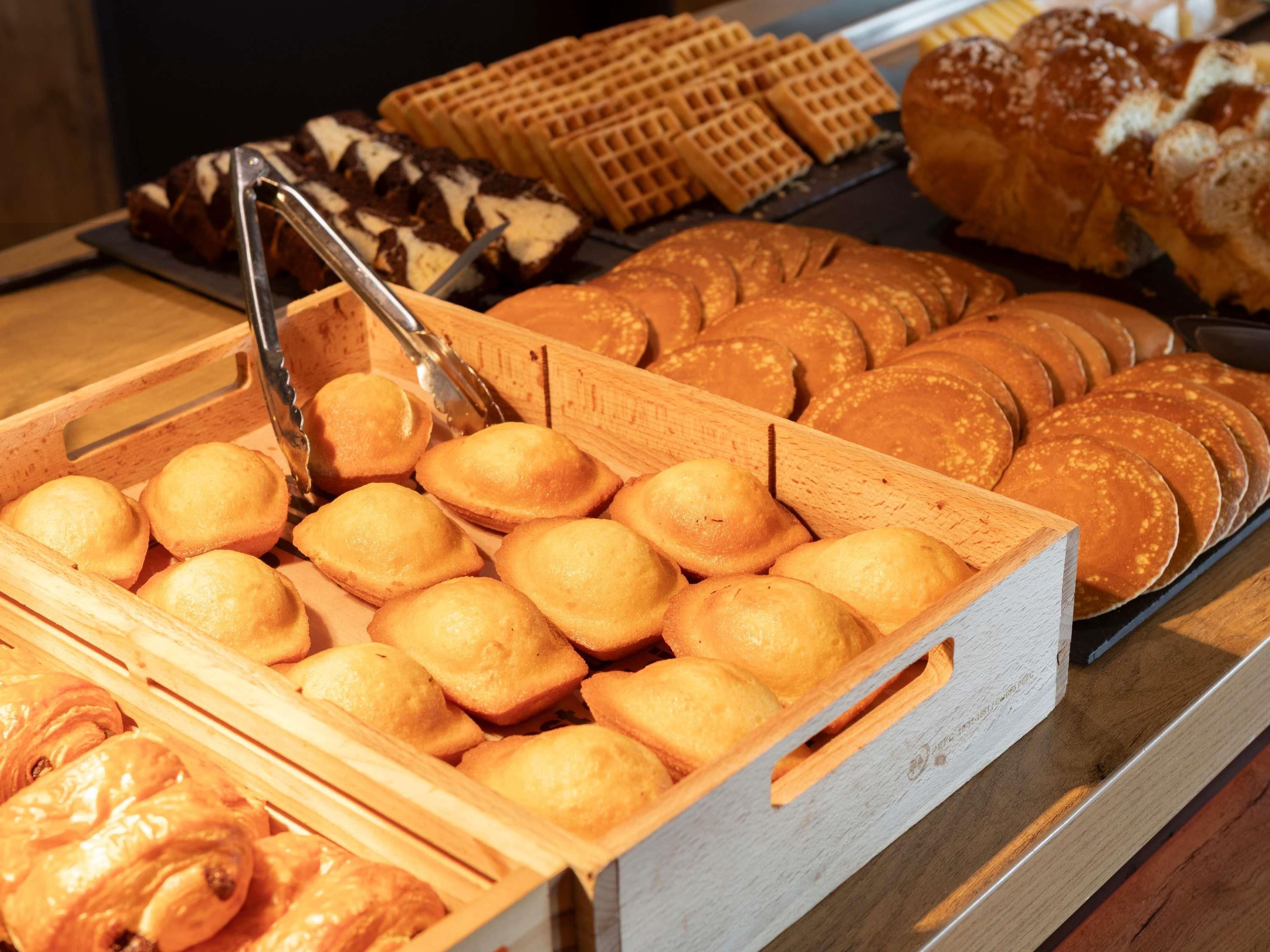 A bakery display with various baked goods including bread, pastries, and waffles.