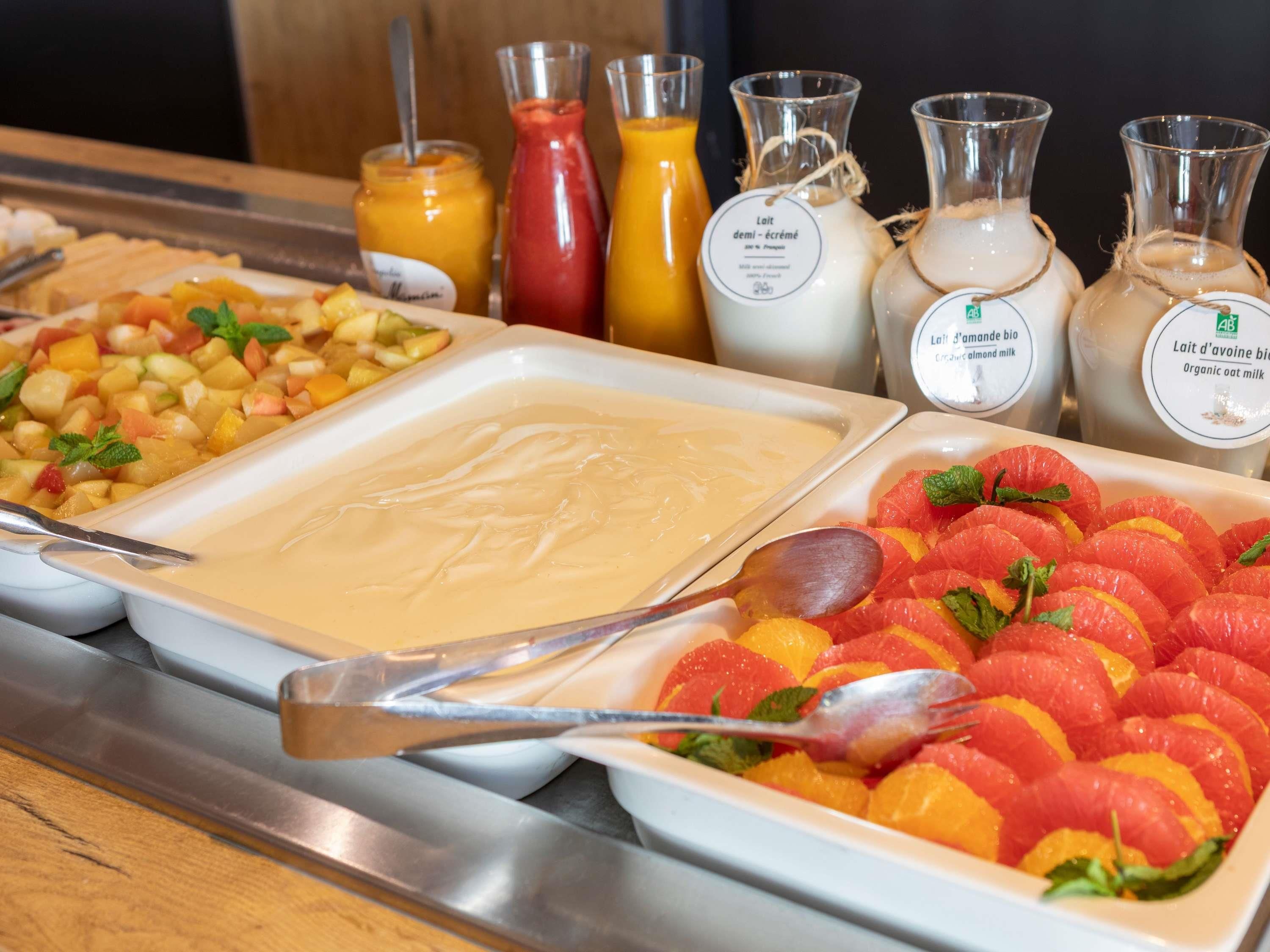 A buffet with various food items including fruit salad, creamy dishes, and different types of milk.