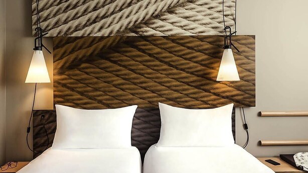 Ein Hotelzimmer mit Bett, Nachttischen, einer Lampe und einer strukturierten Wand.