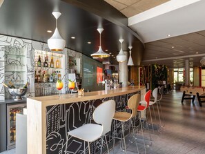 A bar area with a modern design, including a bar counter, seating, and ambient lighting. - ibis Saint Quentin En Yvelines Velodrome (Montigny-le-Bretonneux)