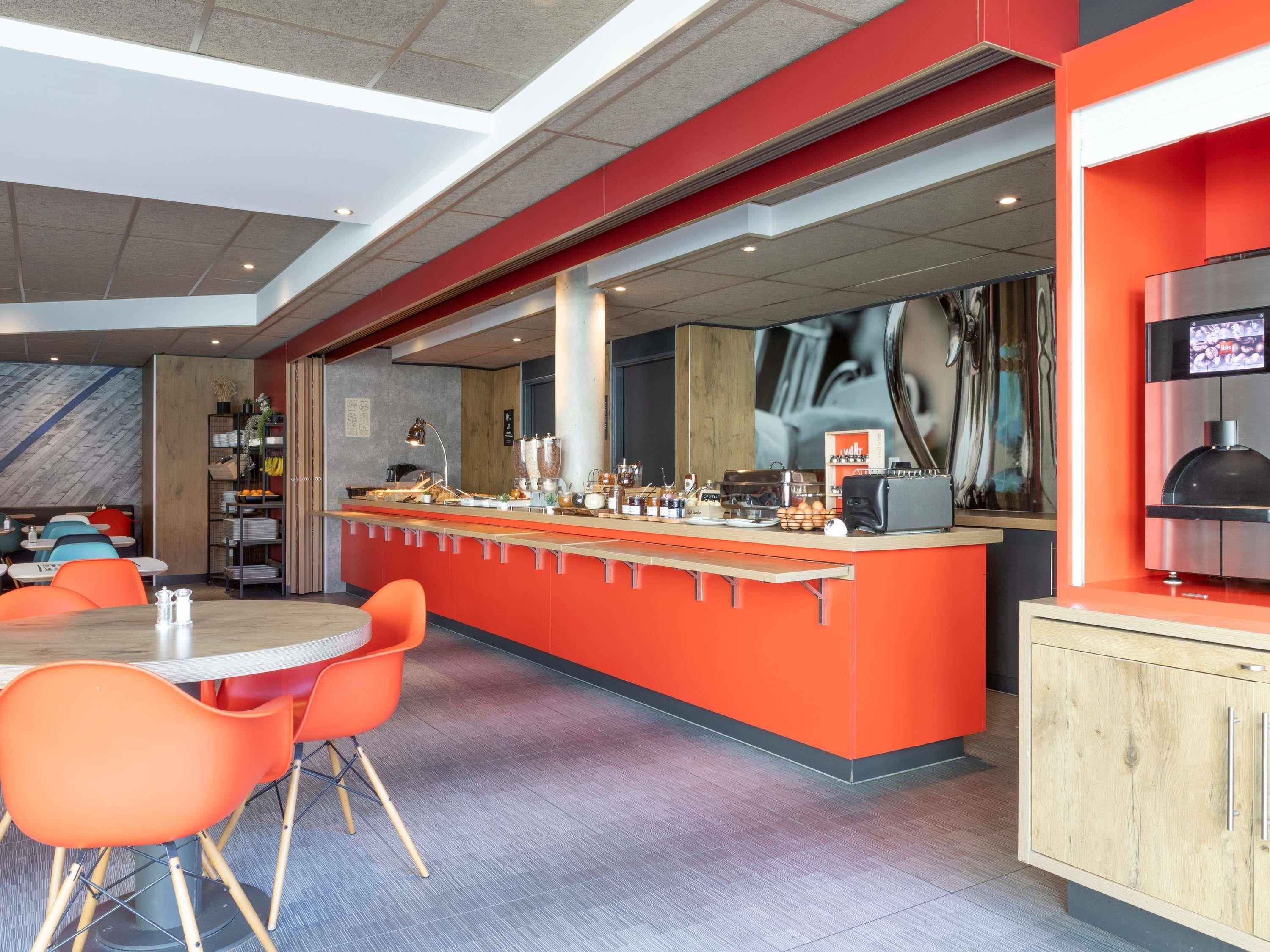 Ein modernes Café mit einer zentralen Bar, Sitzbereich und einem großen Fenster.