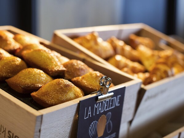 A display of baked goods in wooden boxes with a sign reading 'LA MADELEINE.'