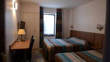 A hotel room with two beds, a desk, a chair, and a window with curtains.