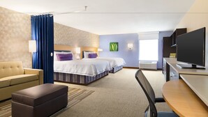 Una habitación de hotel con dos camas, un sofá, un escritorio y una televisión.