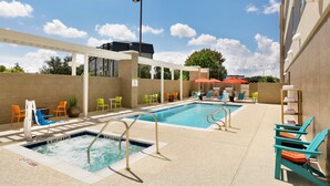 Un área de piscina con varias piscinas, sillas de descanso y sombrillas.