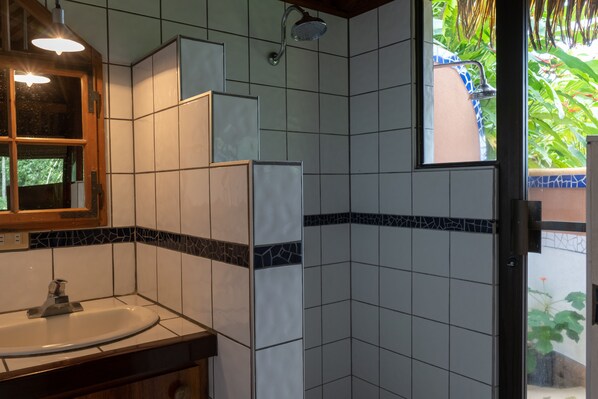 Un baño con lavamanos, espejo y ducha.