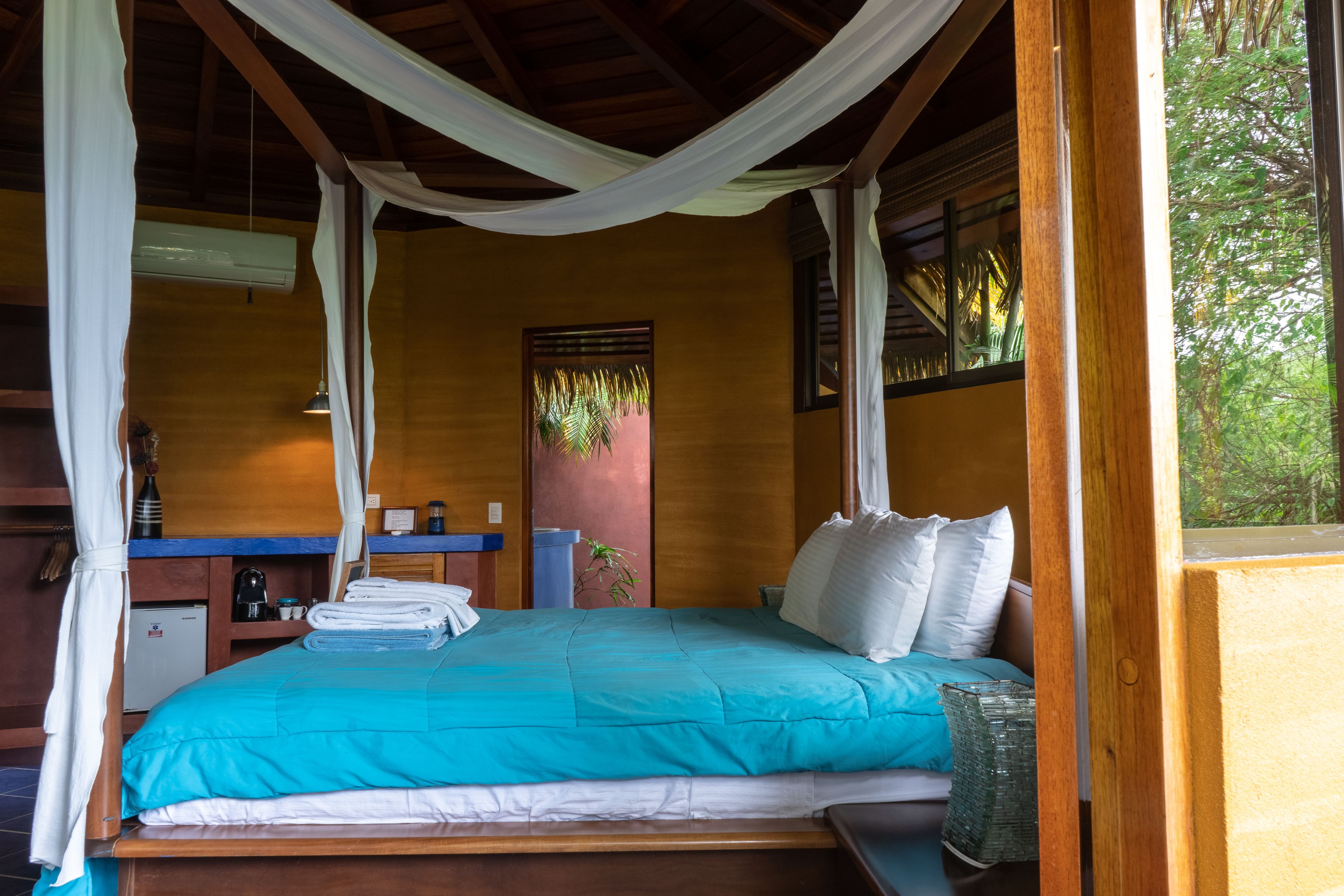 A room with a bed, a nightstand, a small table, and a window with curtains.