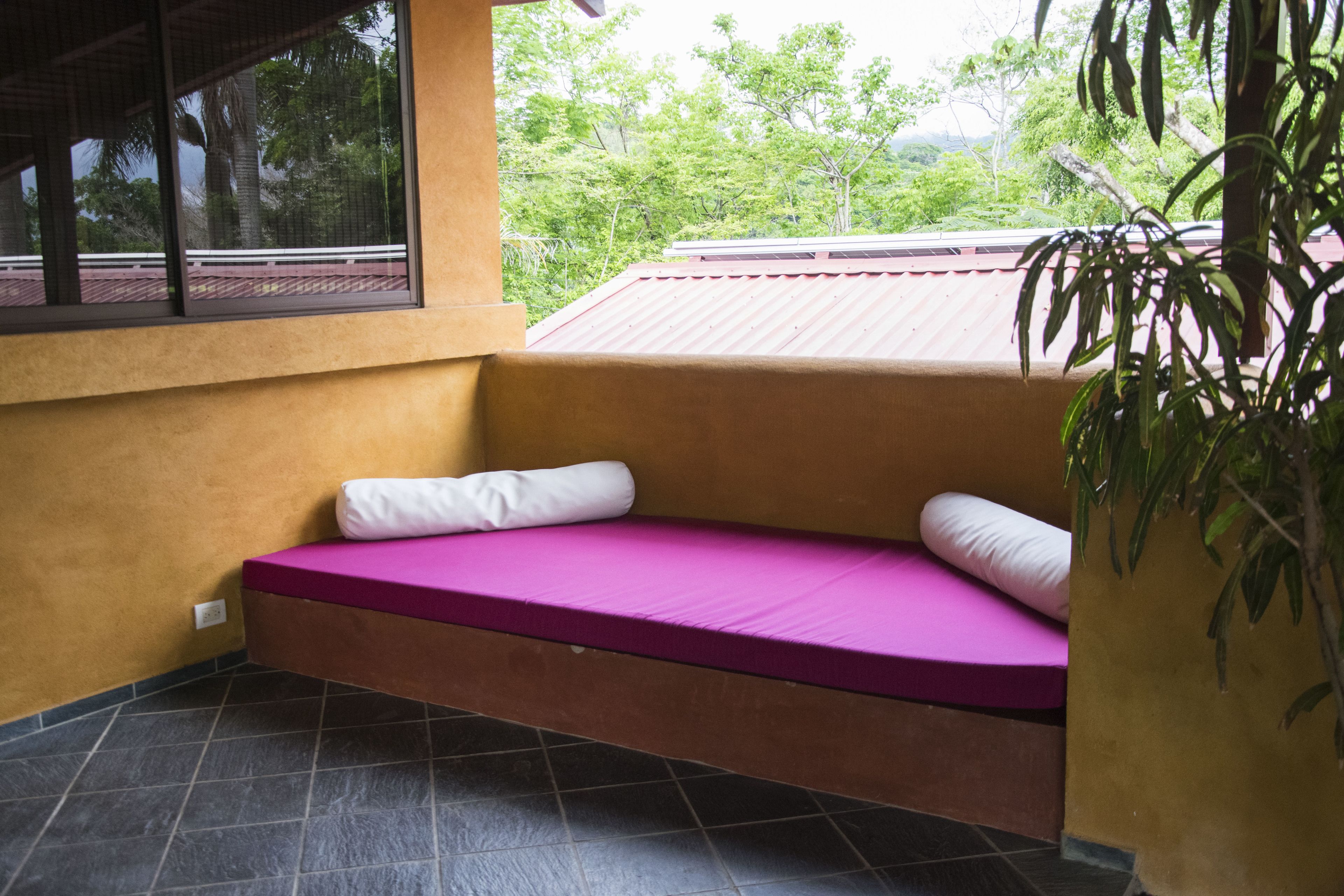 A room with a bed, a window, and a view of greenery.