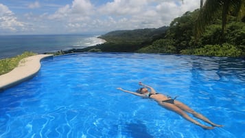 Una piscina al aire libre, sillones reclinables de piscina