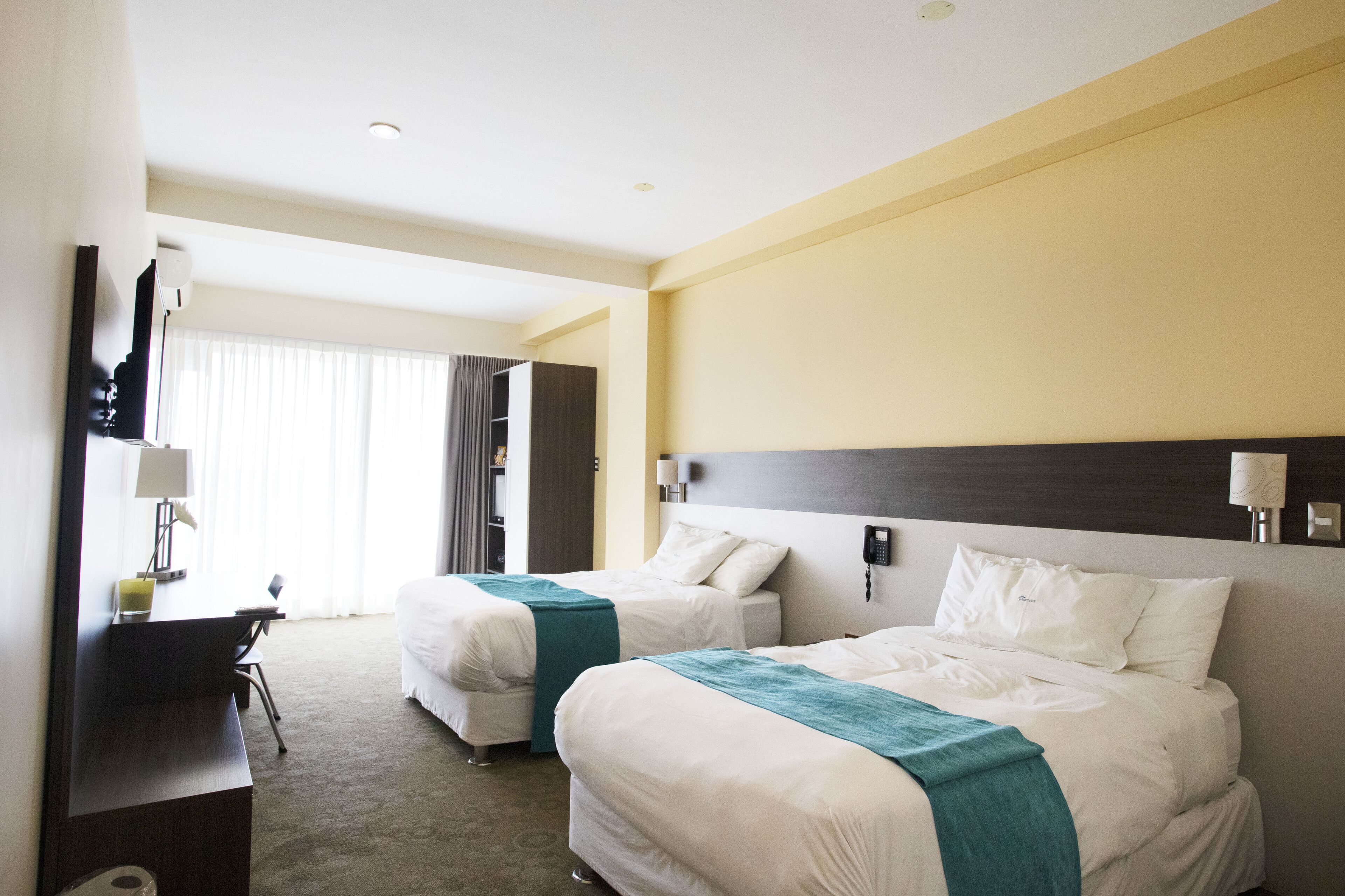 Habitación de hotel con dos camas, un escritorio y una silla.