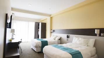 Habitación de hotel con dos camas, un escritorio y una silla.