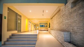 Un hall d’hôtel avec un mur en pierre, un escalier et un comptoir d’accueil.