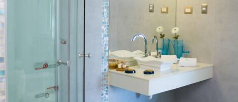 Un baño moderno con ducha de vidrio, tocador con espejo y lavabo.