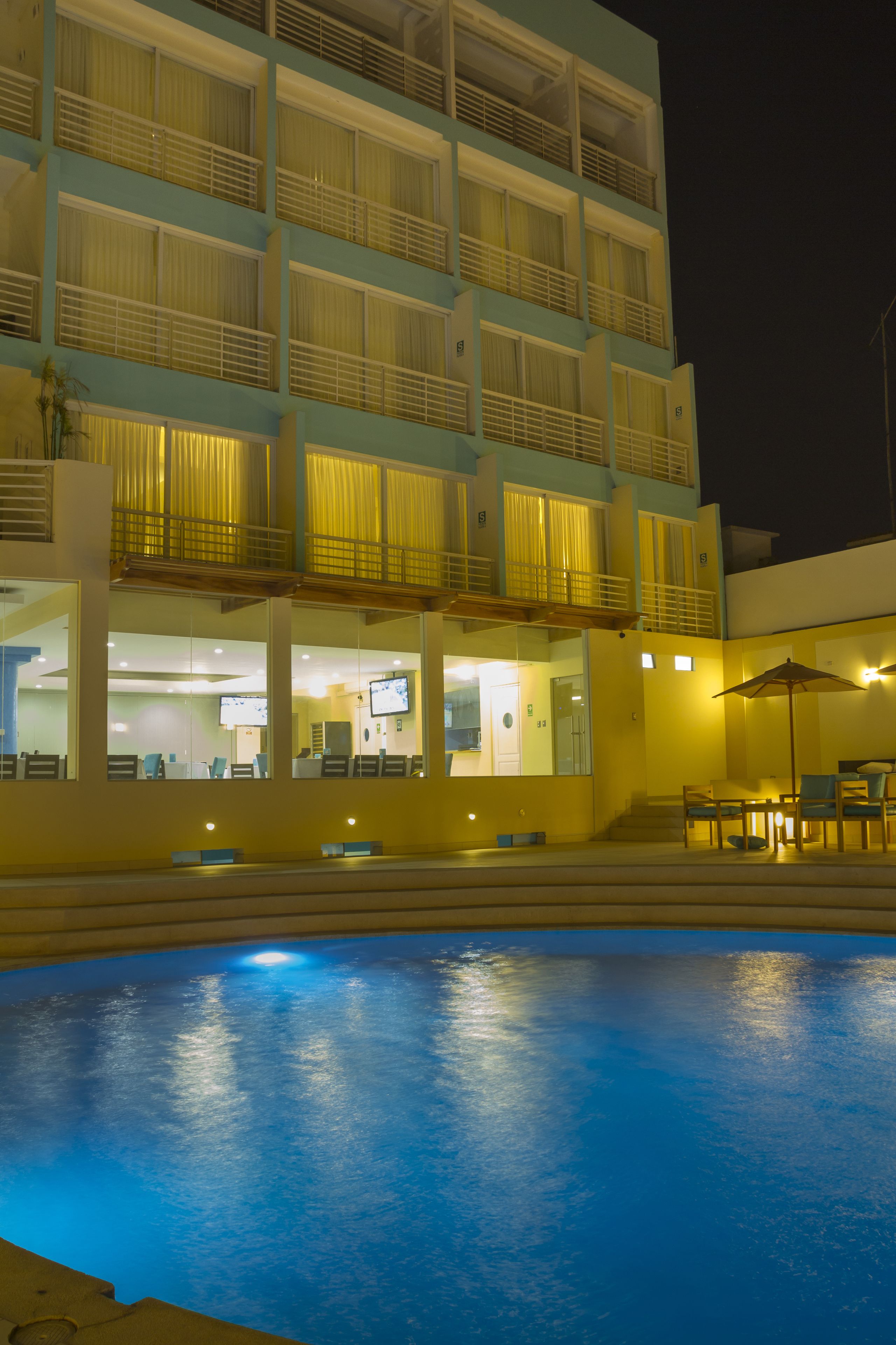 A hotel with a swimming pool, multiple balconies, and outdoor seating.