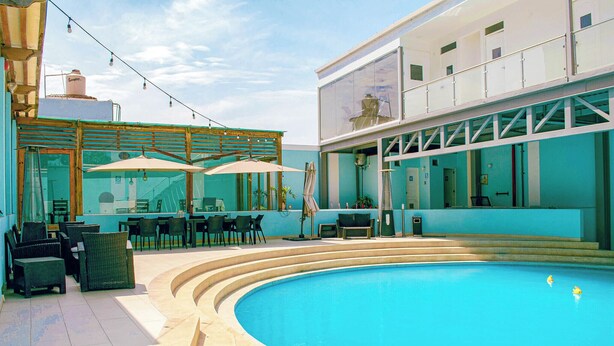 Un espace piscine avec des sièges et des parasols à l’extérieur.
