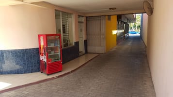 A corridor with a vending machine, a glass door, and a blue car parked outside.