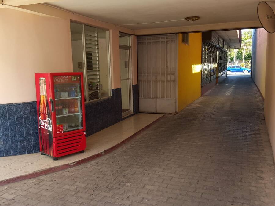 A corridor with a vending machine, a glass door, and a blue car parked outside.