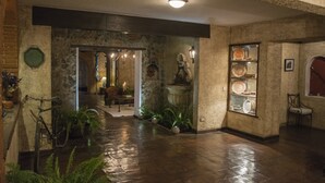 A spacious lobby with a wet floor, stone walls, and a display case with pottery. - Hotel Casa San Lázaro (Antigua Guatemala)
