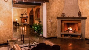 A cozy lobby with a fireplace, a chandelier, and a seating area. - Hotel Casa San Lázaro (Antigua Guatemala)