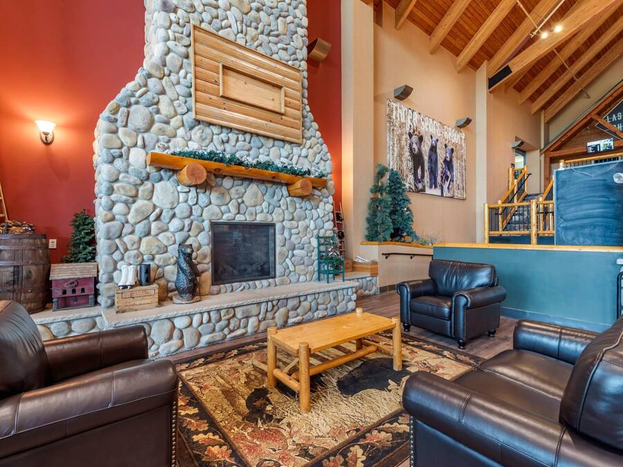 A cozy living area with a stone fireplace, leather sofas, and a wooden coffee table.