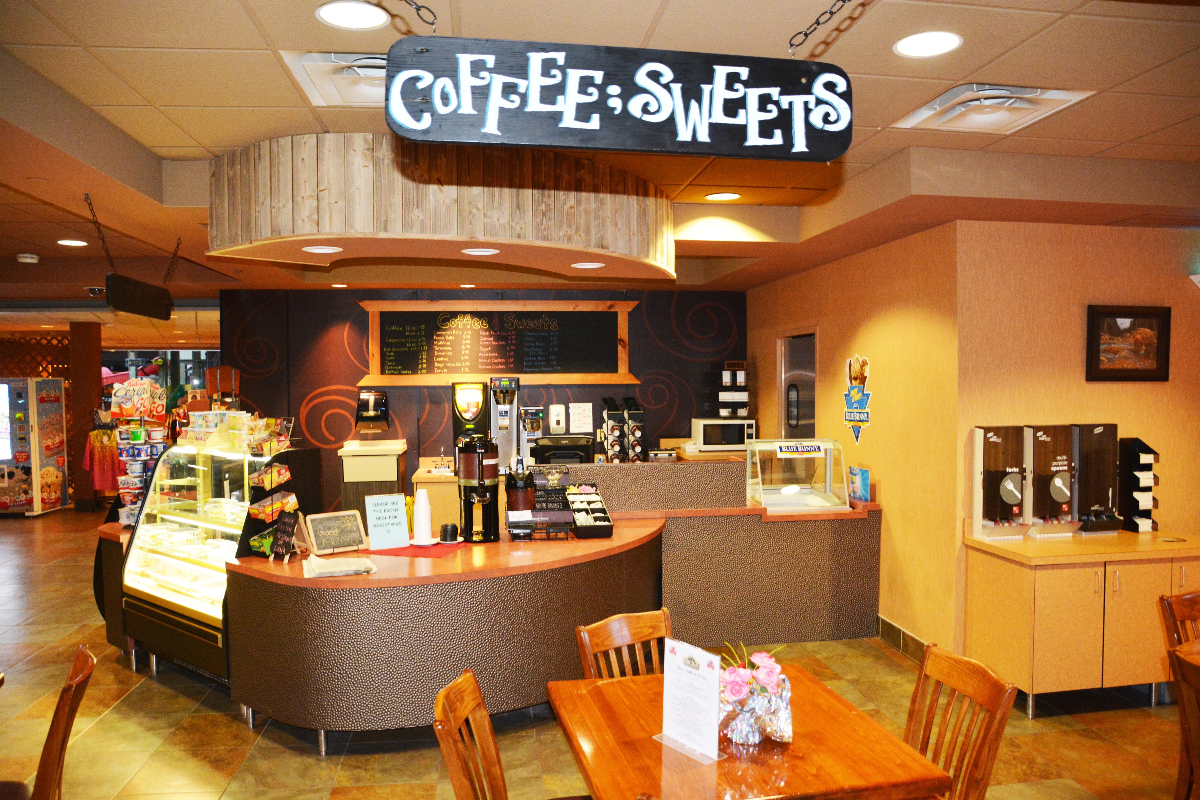 A coffee shop with a counter, menu board, and seating area.
