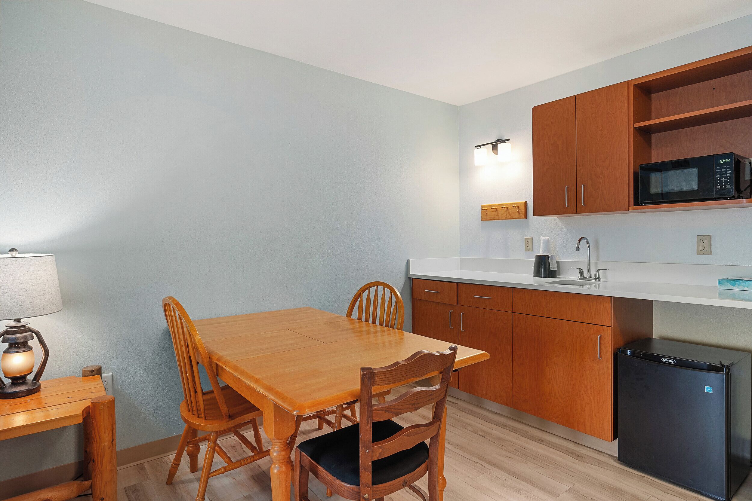 A compact kitchen with wooden cabinets, a microwave, and a refrigerator.