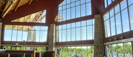 A spacious indoor area with high ceilings, large windows, and wooden furniture.