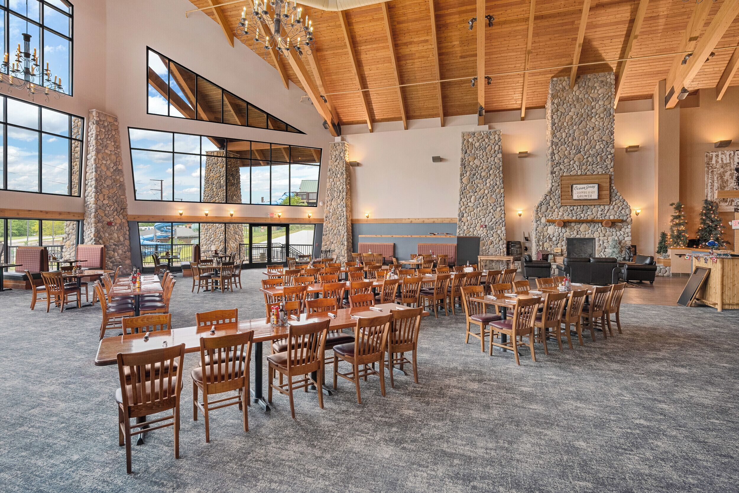 A spacious indoor dining area with high ceilings, stone pillars, and large windows.