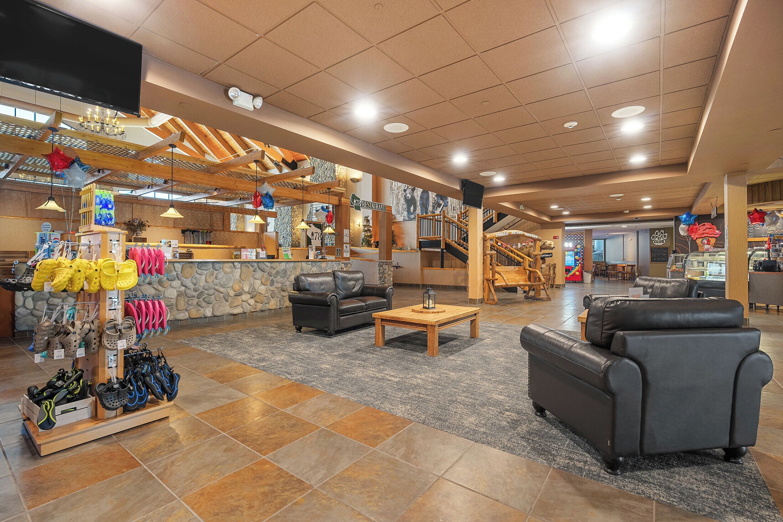 A spacious lobby with a shoe display, a black leather sofa, and a staircase leading to upper floors.
