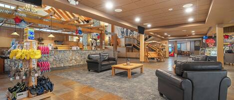A spacious lobby with a shoe display, a black leather sofa, and a staircase leading to upper floors.