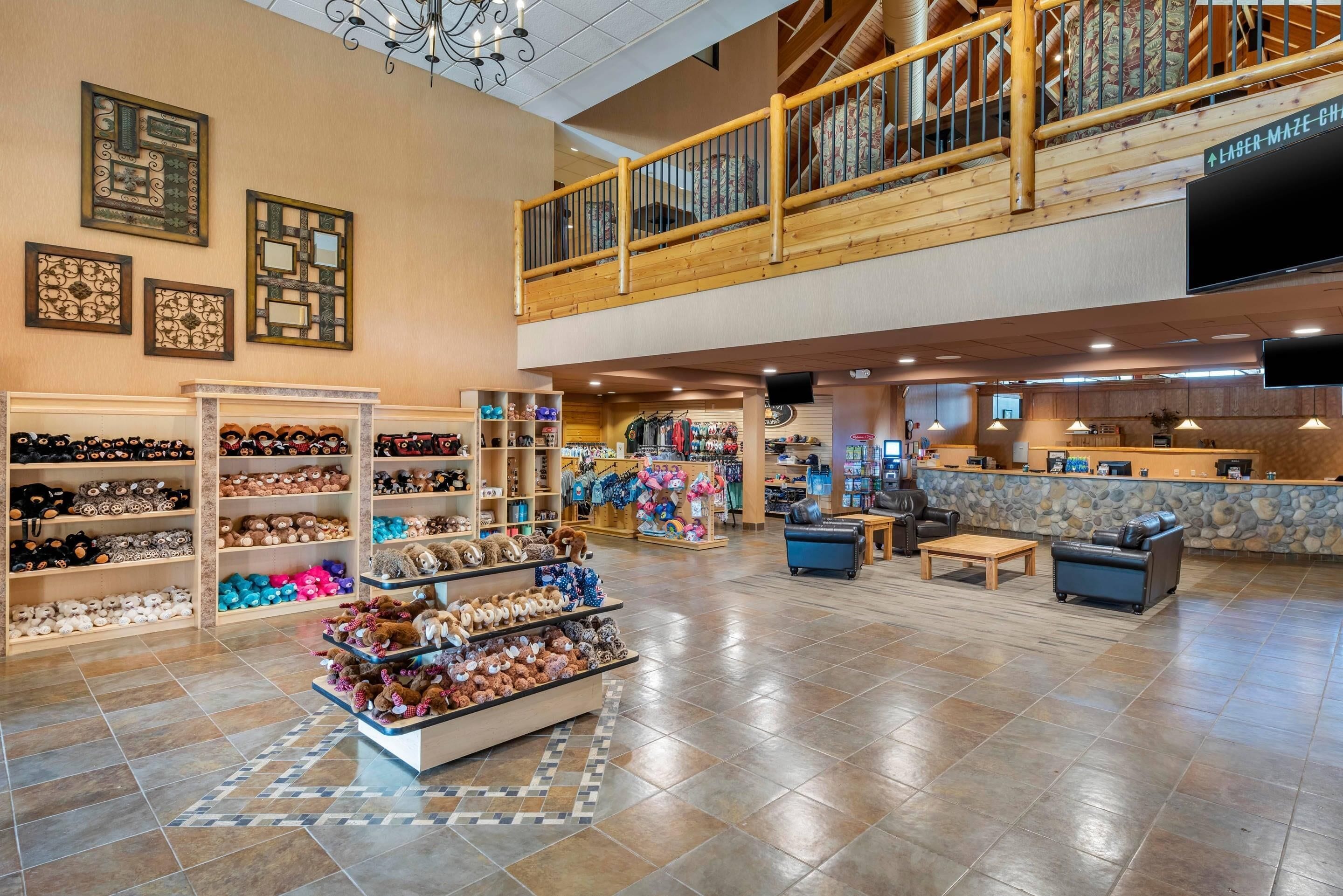 A spacious lobby with a high ceiling, wooden railings, a display of plush toys, and a counter area.