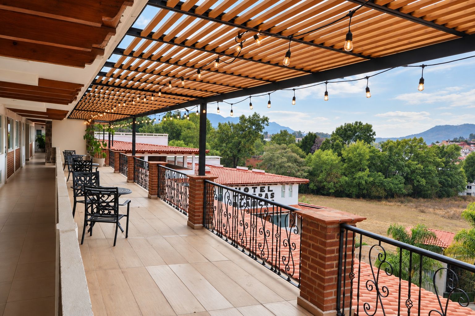Un balcón de hotel con una pérgola de madera, mobiliario exterior y vistas del paisaje circundante.
