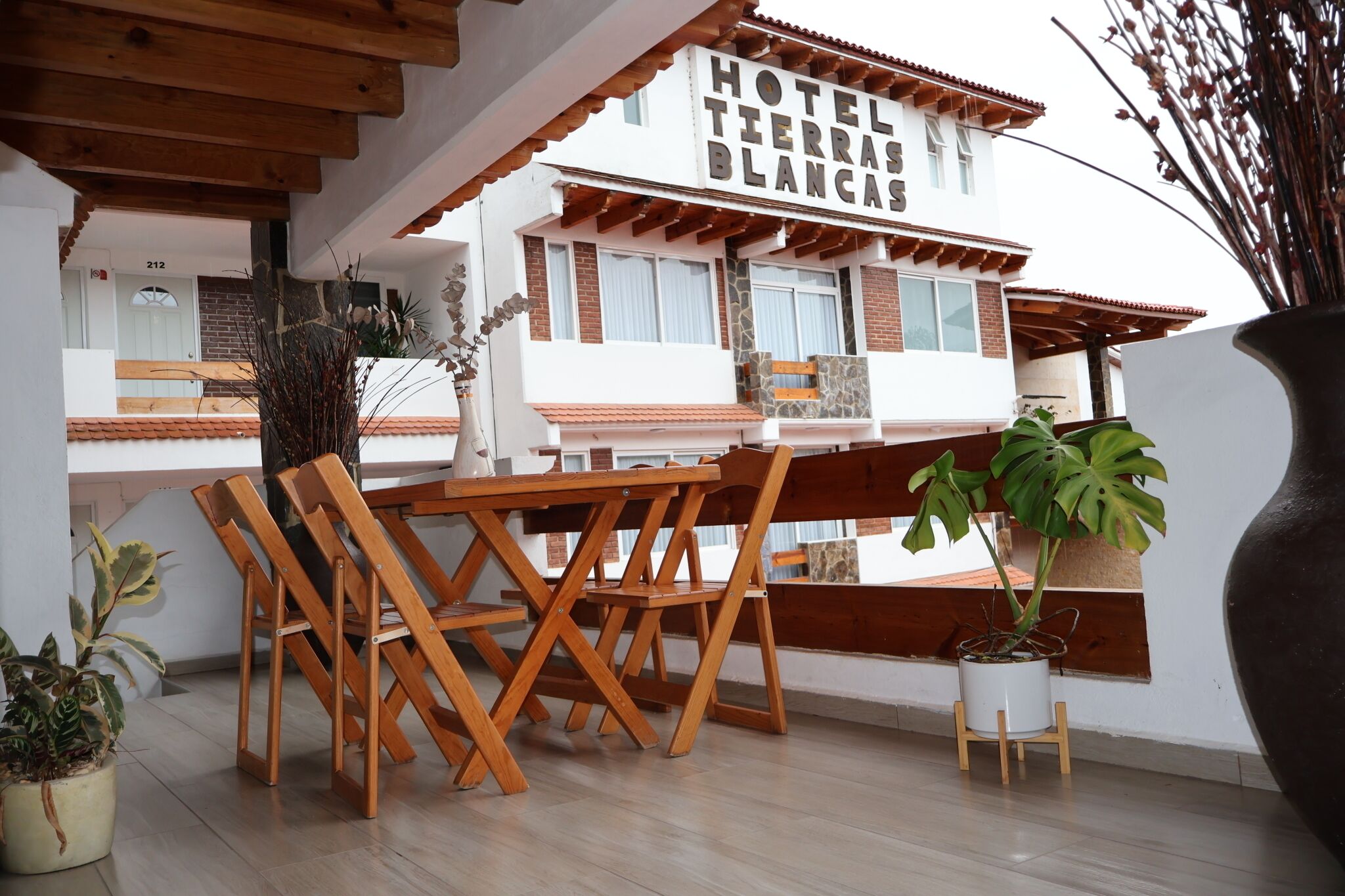 Ein Hotel mit Terrasse, Holzmöbeln und Topfpflanzen.