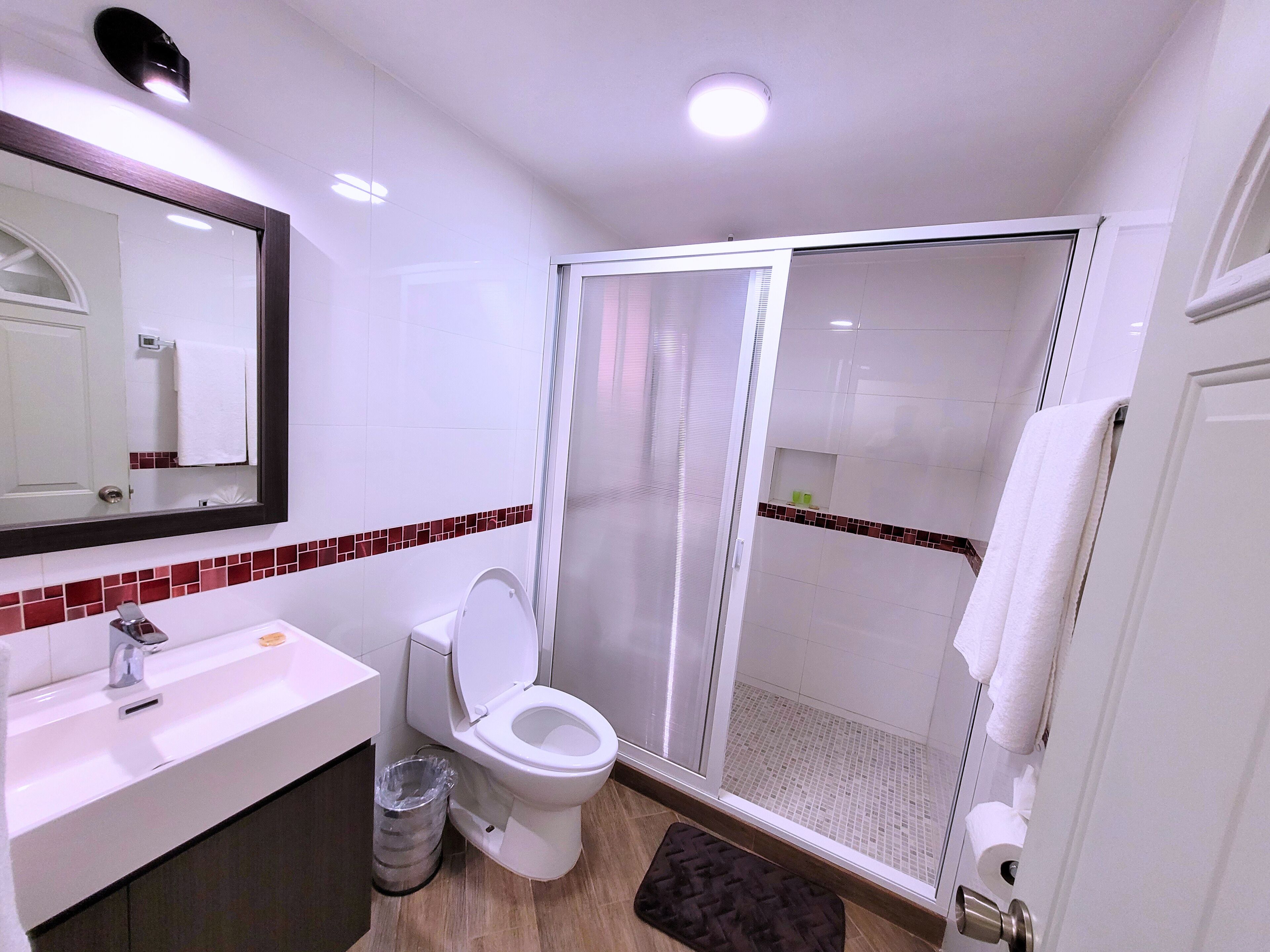 Ein modernes Badezimmer mit Waschbecken, Toilette und Duschbereich in Weiß.