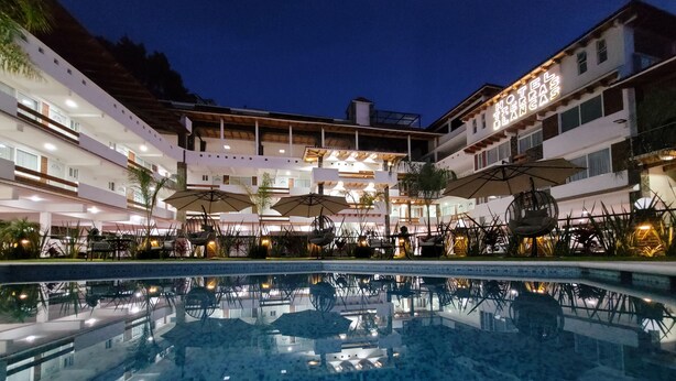 Un hotel con piscina, zona de estar al aire libre y fachada bien iluminada.
