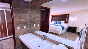 Un baño moderno con un espejo grande, una bañera y una zona de ducha.