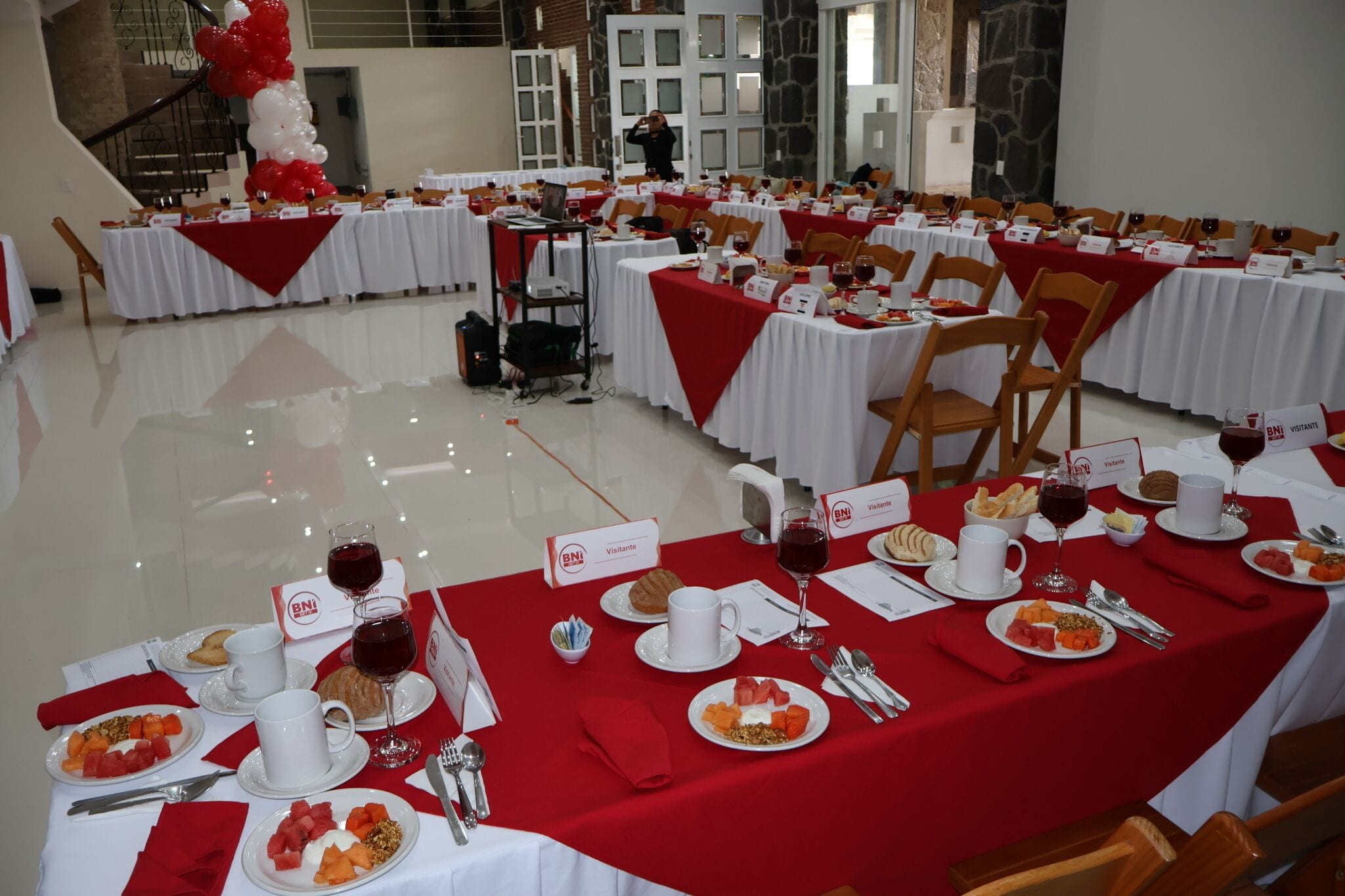 Une salle de banquet avec des tables dressées pour un repas, des étiquettes nominatives et des verres à vin.