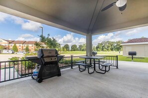 A covered patio with a grill, picnic table, and benches. - Suburban Studios Donaldsonville - Gonzales (Donaldsonville)