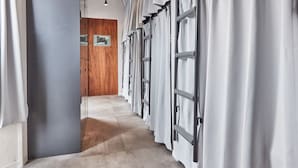 A corridor with a wooden door at the end, leading to a room with a large window and a framed picture on the wall. - Tora Hotel Asakusa - Hostel (Tokyo)