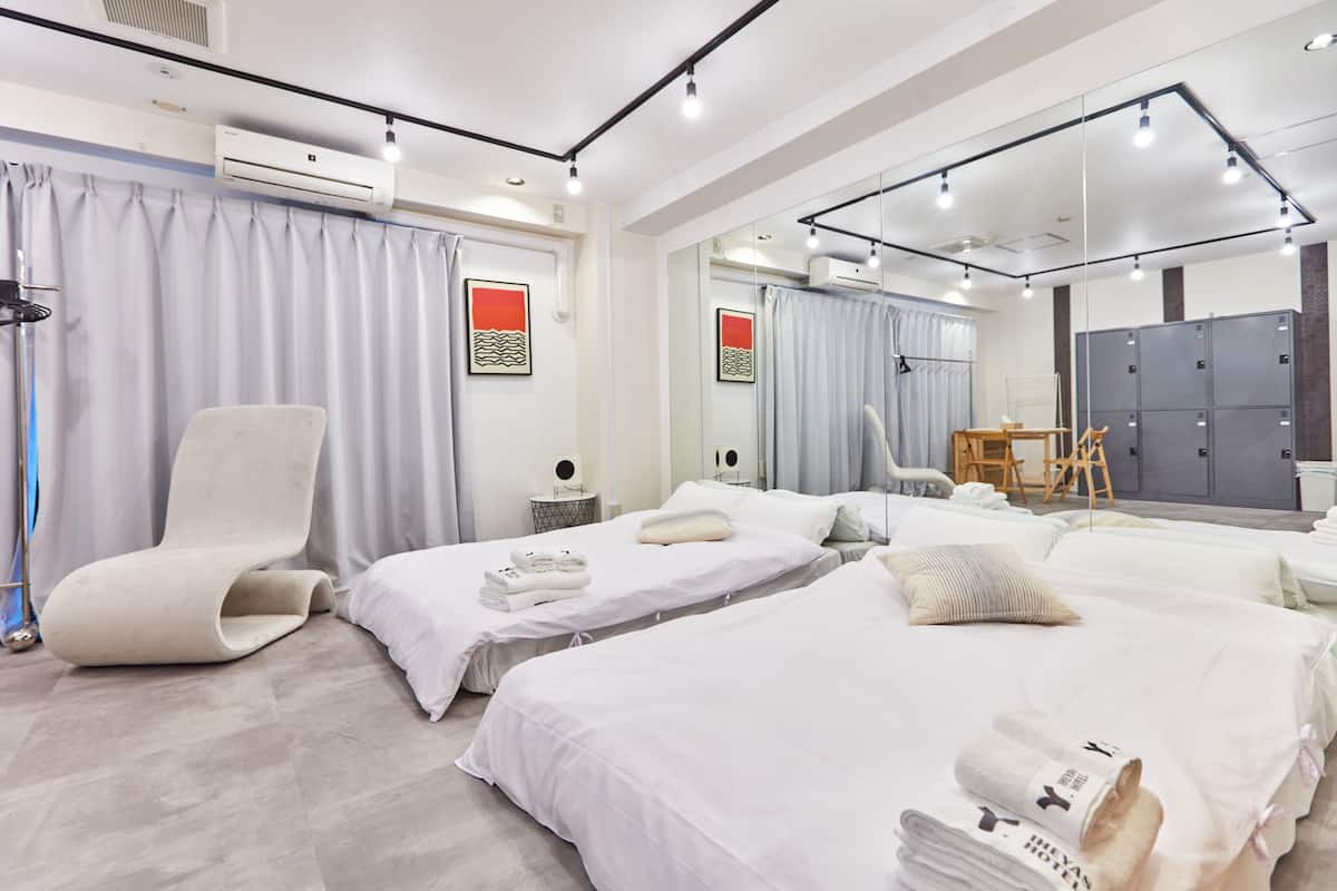 A hotel room with two beds, a large mirror, a chair, and a desk with a chair.